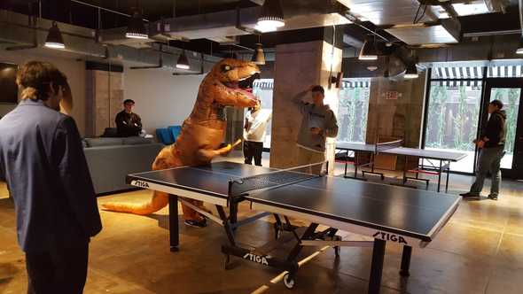 T-Rex playing ping-pong in DevMountain Lounge