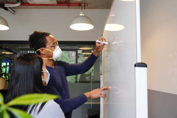 Man writing on whiteboard wearing face mask