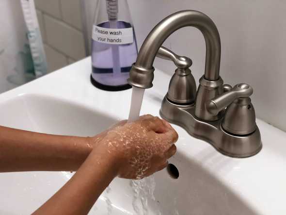 person washing hand on faucet